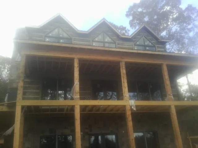 Dormers and porch framing on a large log home under construction — Roof Coating work by our crew in Lyles