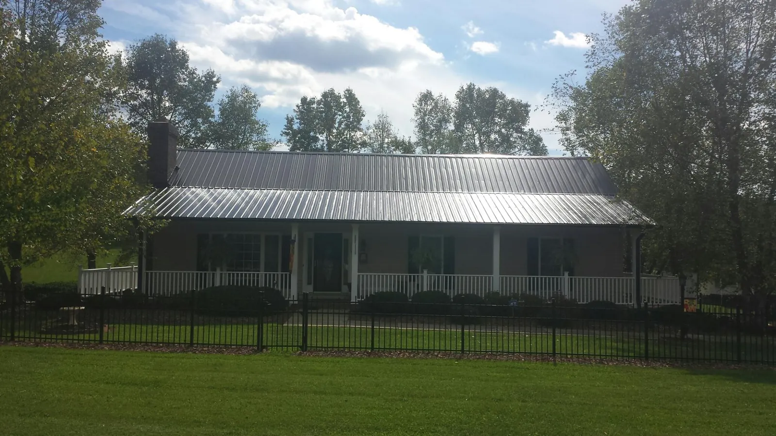 Gray metal roof on a brick ranch with a full width front porch — Gutter Guard Installation work by our crew in Lyles